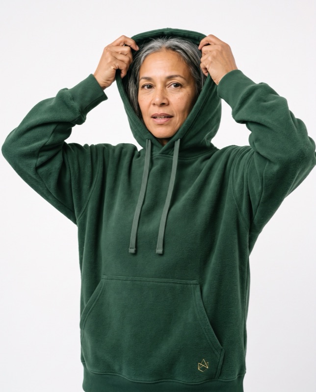 A model pulling up the hood of a forest green pullover hoodie